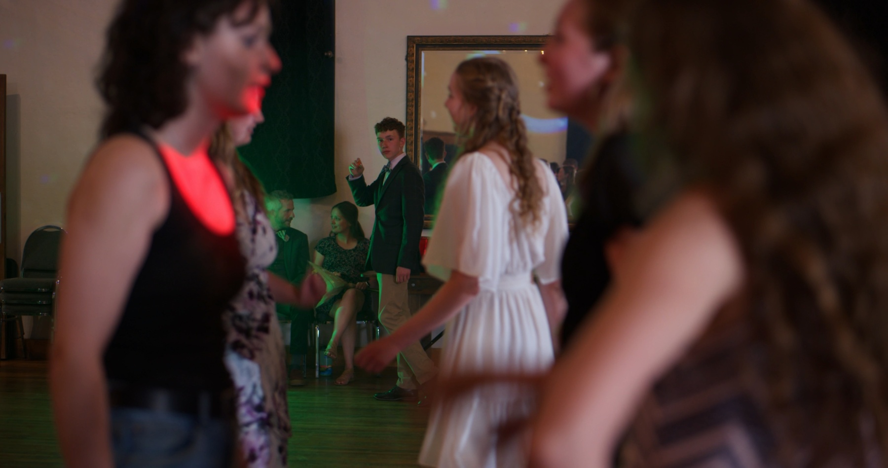 Teens dance under colored lights at a formal.