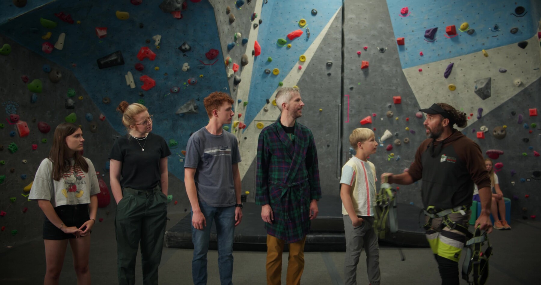 A group lines up at a climbing gym, listening to their guide.