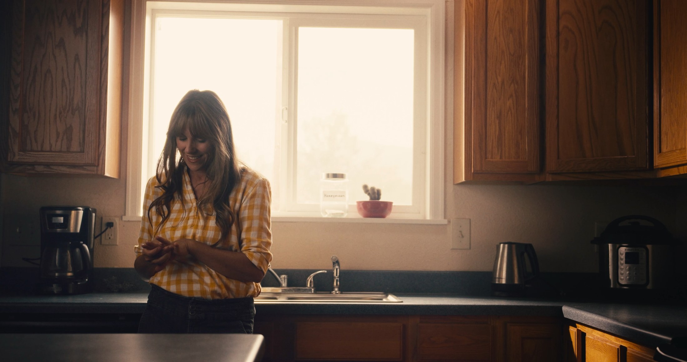 A sunlit moment from Junction: Maggie stands at the kitchen window.