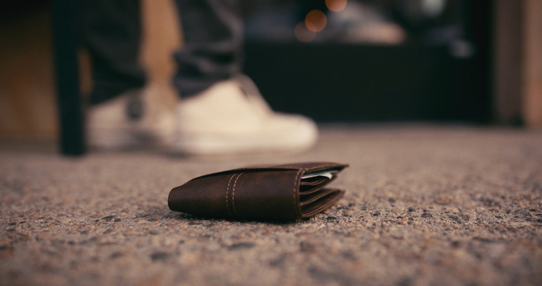A wallet lies on the pavement as a figure walks away in Junction.