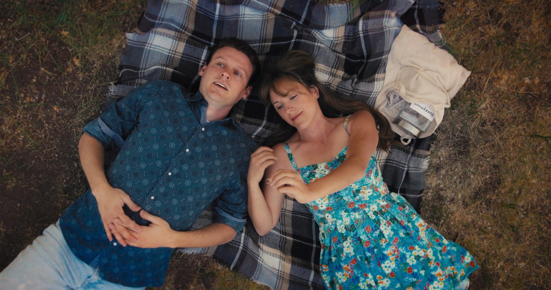 An overhead shot of Milo and Maggie lying on a picnic blanket.