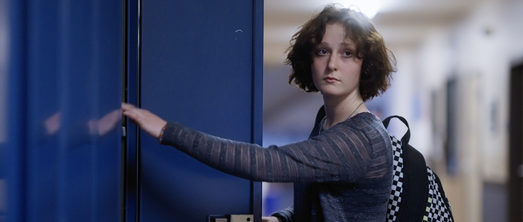 Sadie pauses with her hand on a blue doorway.